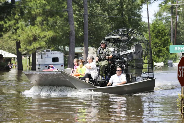 Rescue crew on an airboat carrying residents through floodwater in Vidor, Texas, after Hurricane Harvey