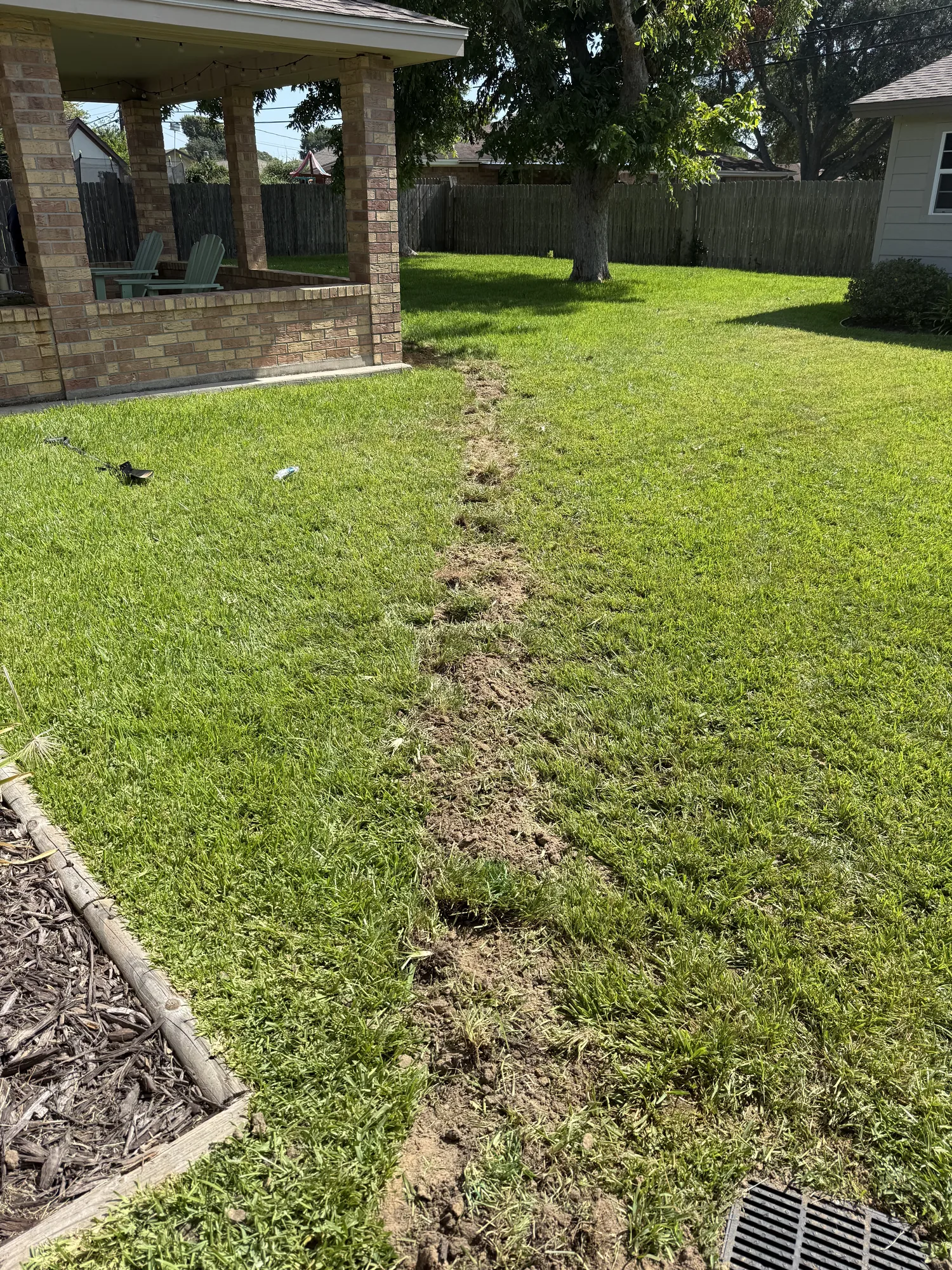 Drain line reroute trench running the length of the backyard in Port Neches, TX