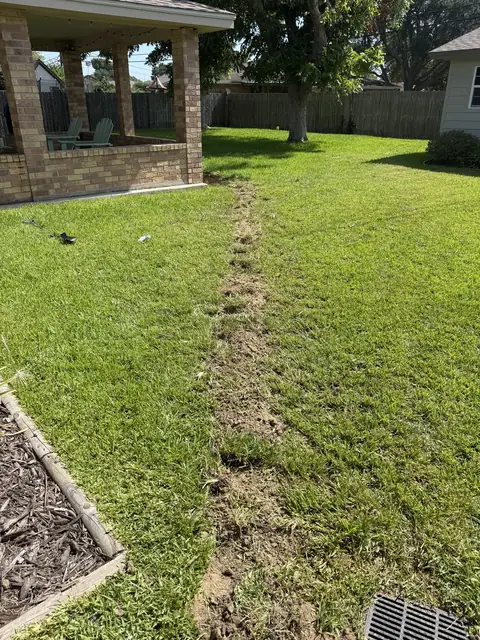 Drain line reroute trench running the length of the backyard in Port Neches, TX