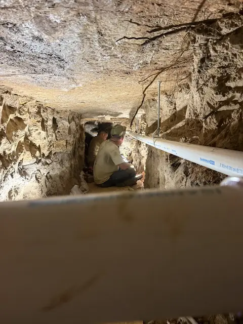 Two crew members re-piping inside a hand-dug tunnel under a Beaumont, TX slab
