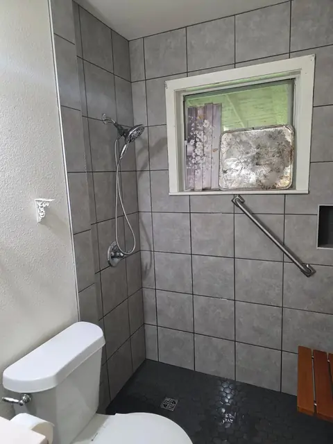 Walk-in shower with a handheld shower head and grab bar in Orange, TX