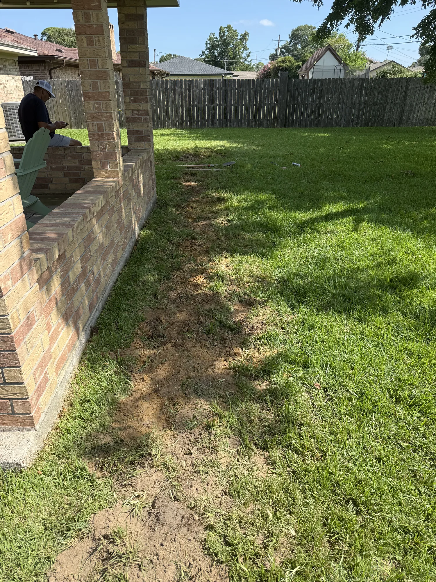 Rerouted washing machine drain line trenched beside the foundation in Port Neches, TX
